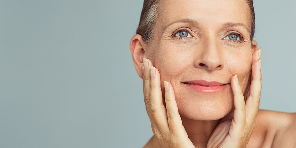 Happy older woman touching her face