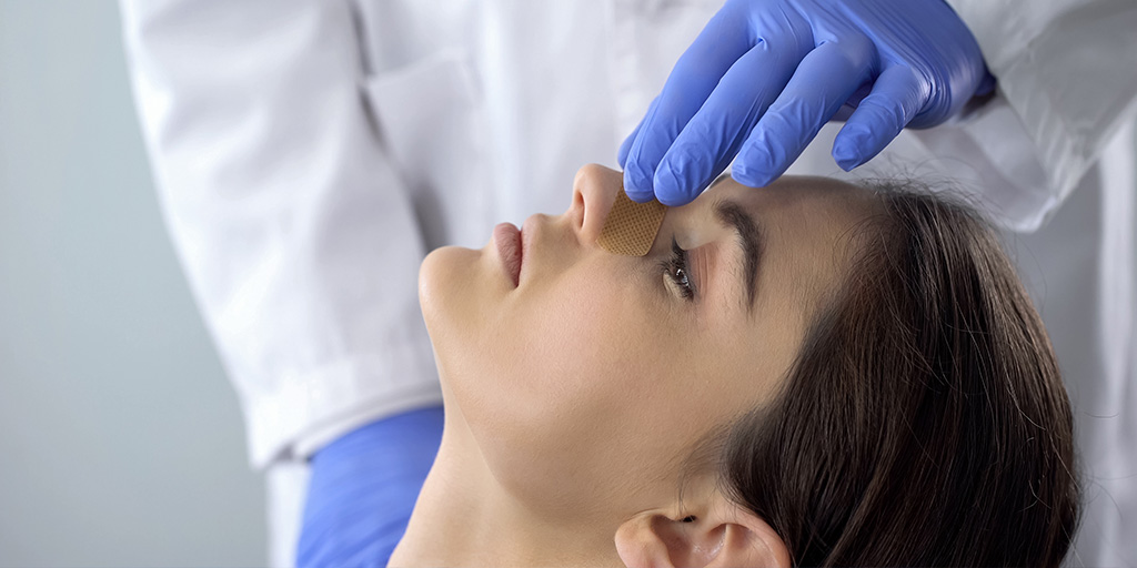 Doctor checking woman's nose