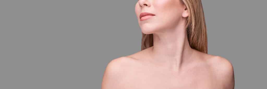Woman with bare shoulders and long blonde hair looks to the side, highlighting natural beauty after plastic surgery.