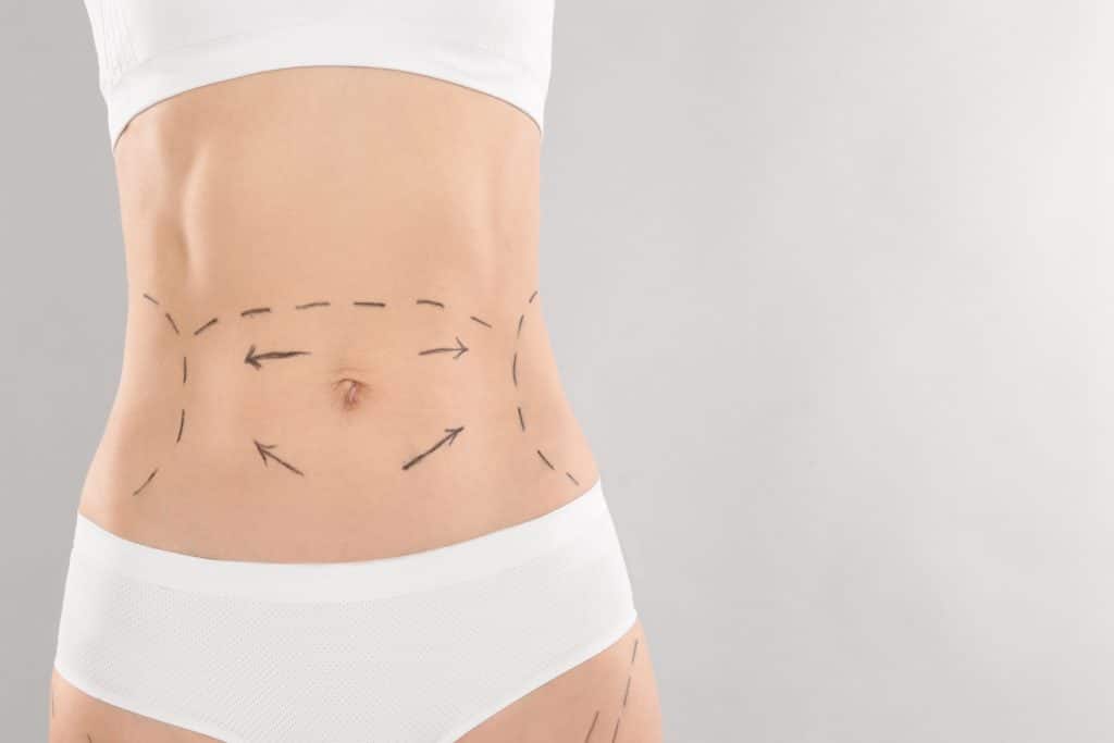 A close-up of a woman's midsection marked with dashed lines and arrows, illustrating areas of focus along the abdomen, waist, and hips.