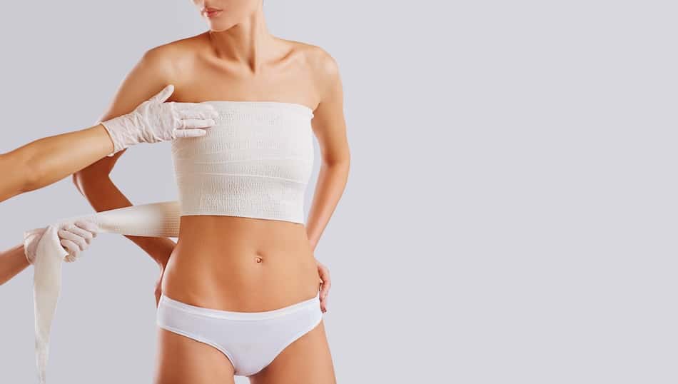 A person in white underwear is having their chest bandaged by someone in medical gloves.