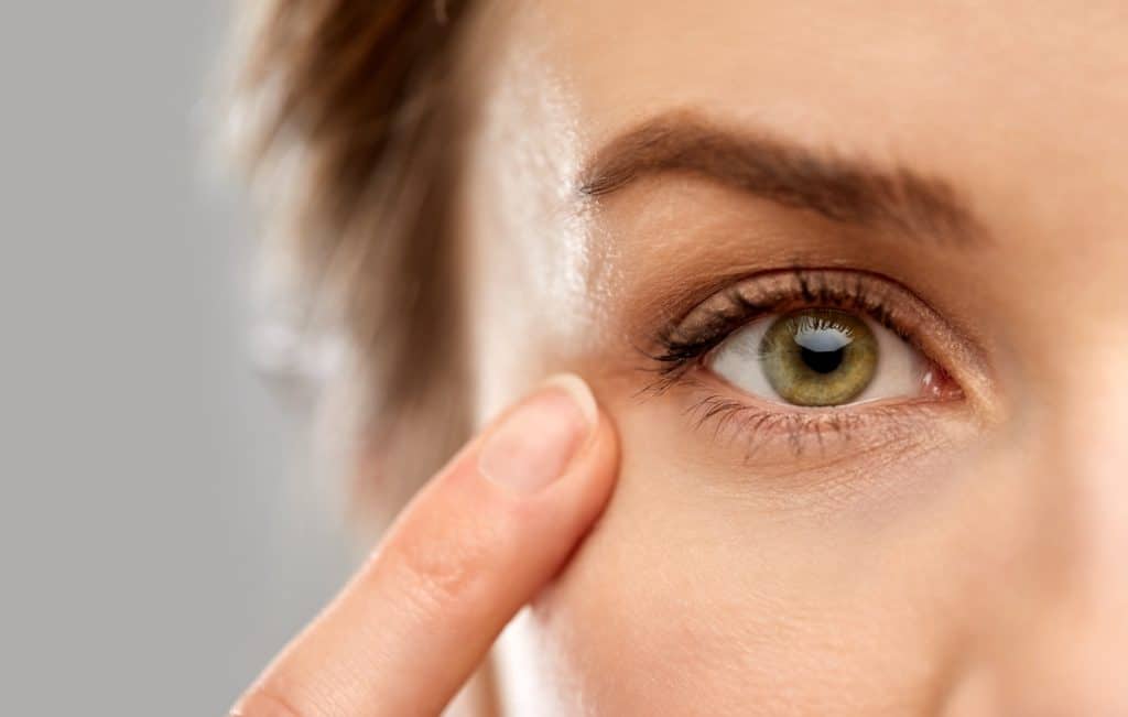 Close up of woman pointing finger to eyelid