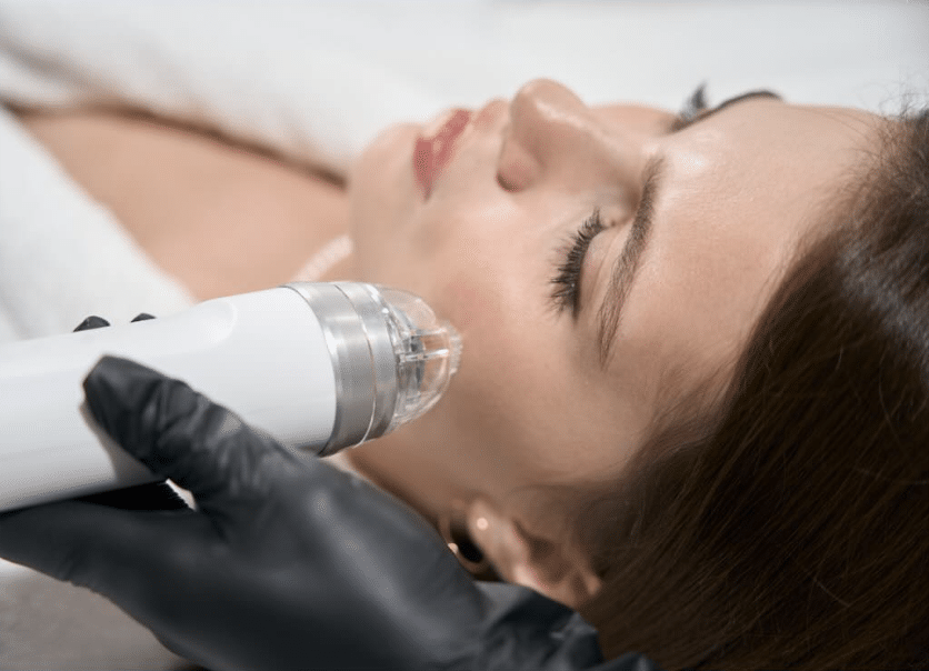 A person receives a facial treatment with a handheld device operated by a gloved hand.